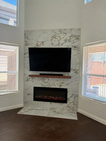 Marble-tile fireplace feature wall with mounted TV and floating mantel — CertiPro remodel