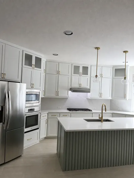 Second angle of a white kitchen remodel with custom island and gold pendant lighting — CertiPro remodel