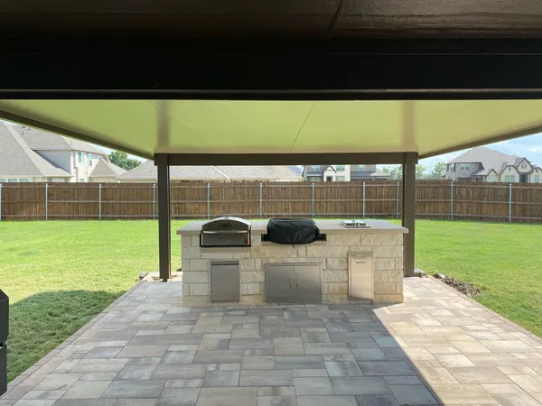 Outdoor kitchen island with built-in grills under a solid insulated patio cover — CertiPro project
