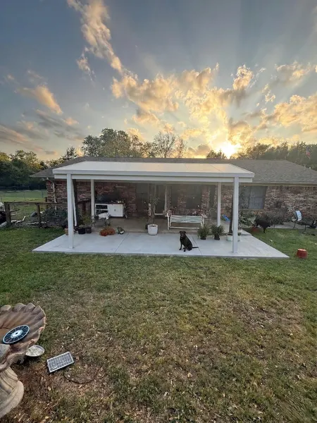 Front view of a lit freestanding patio cover on a new concrete slab under a sunset sky — CertiPro project, DFW