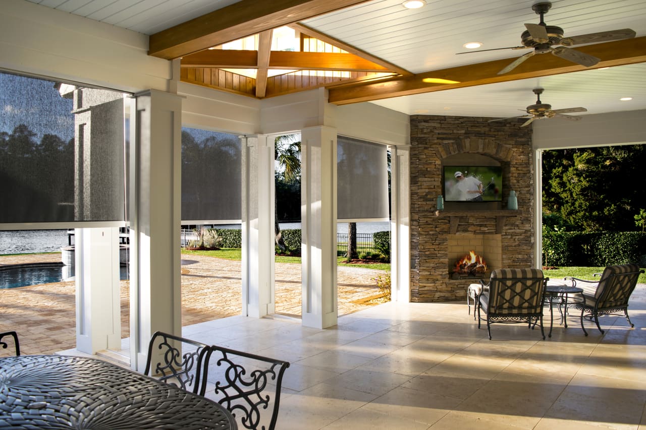 Motorized shade screens lowered across a covered patio